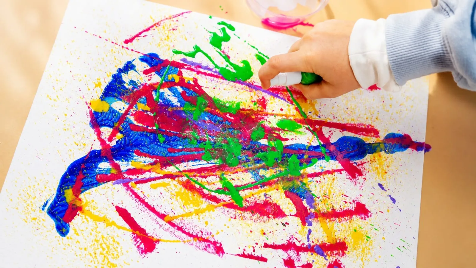 A child’s hands painting at the Enso Art Therapy studio table